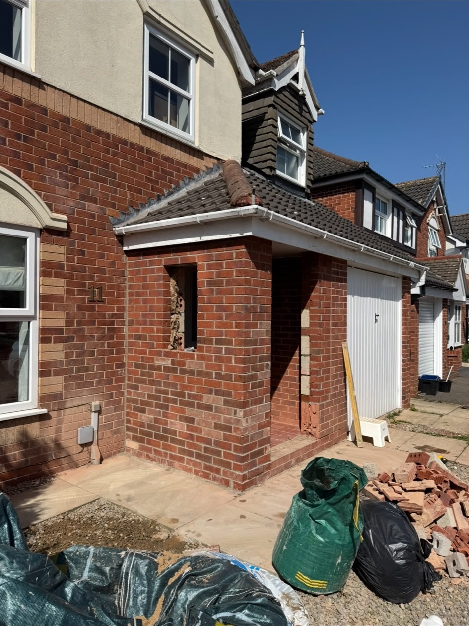 Brick porch build in progress beside an existing house